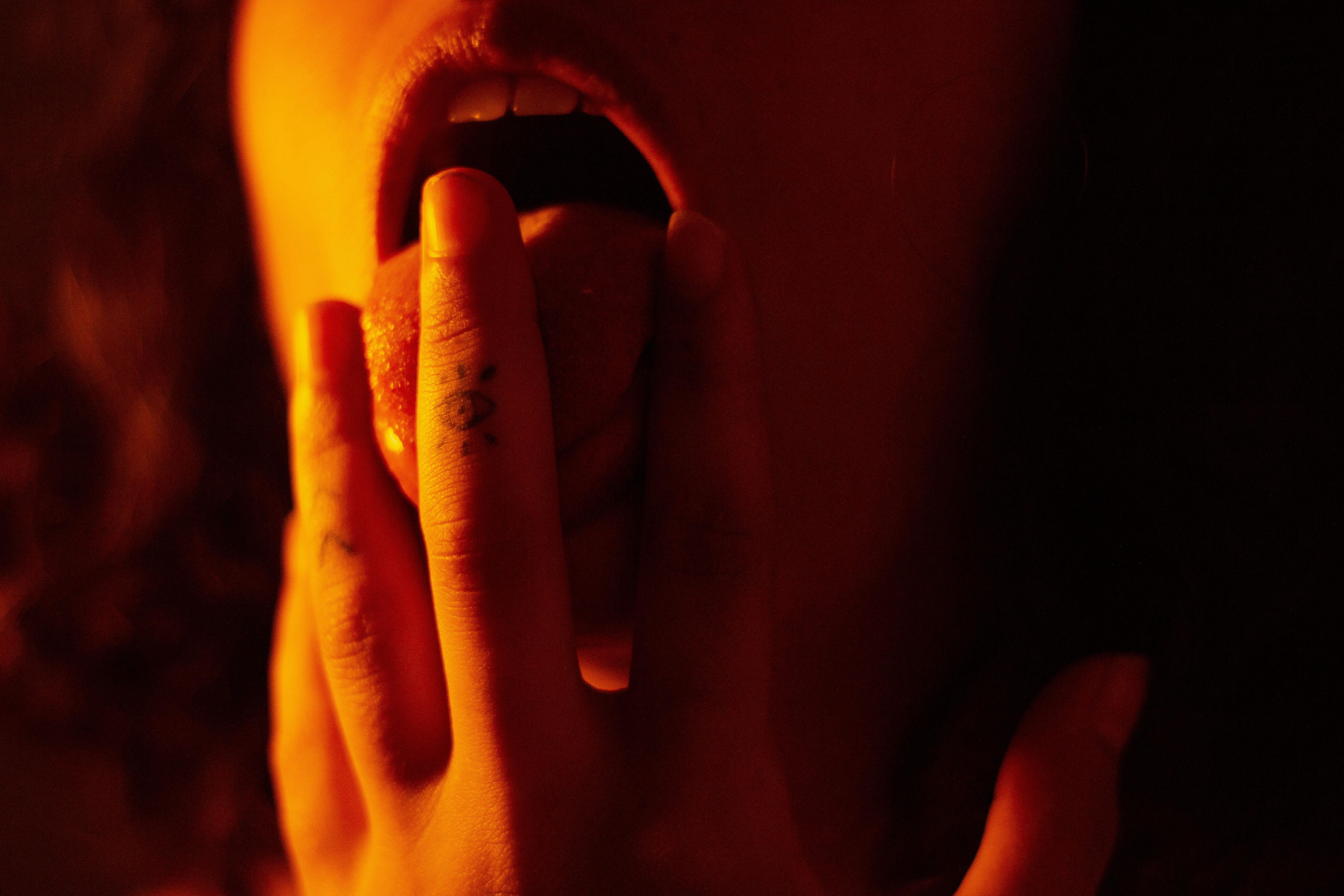 fingers with tattoo playing with woman's tongue