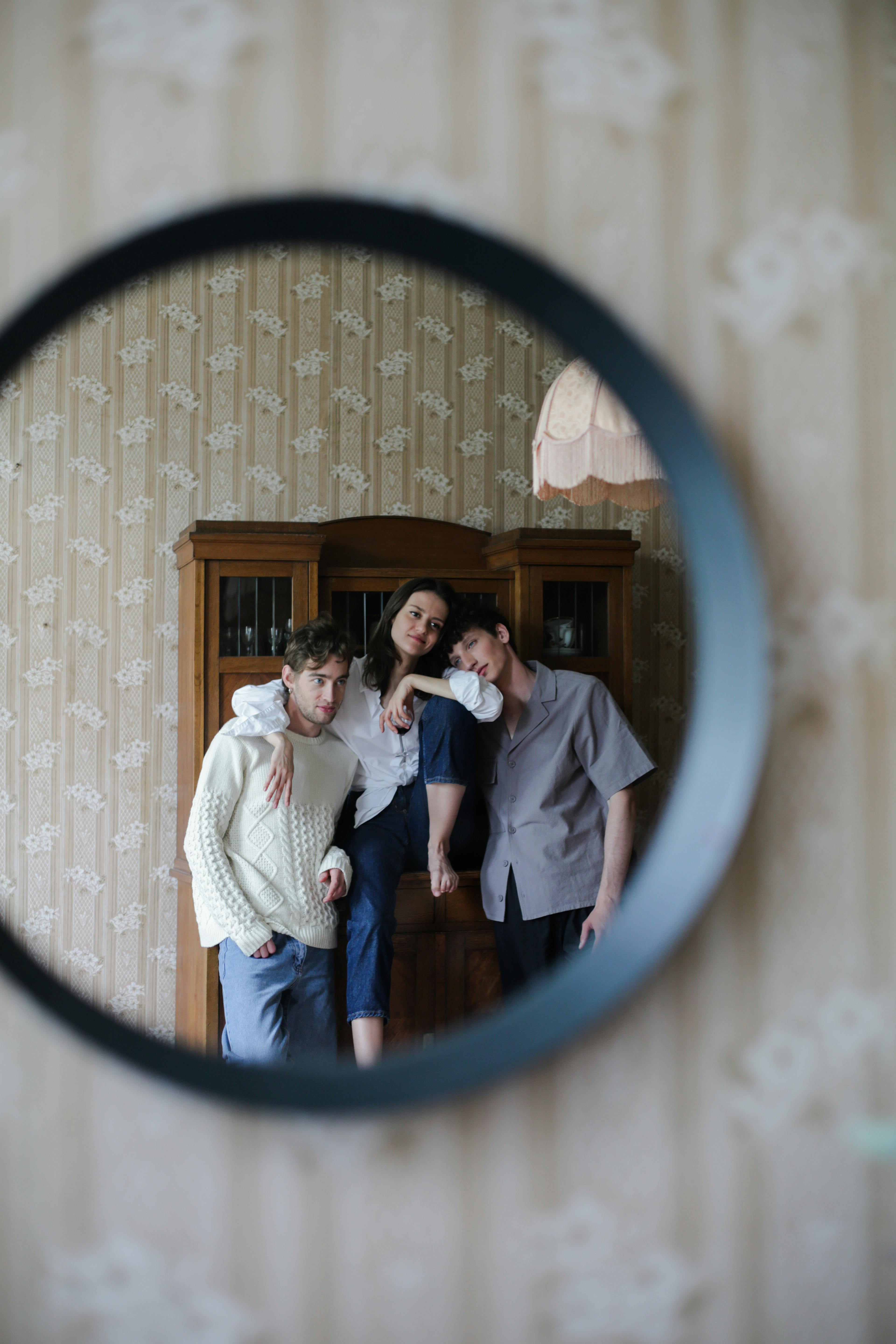 woman between men standing in front of a mirror